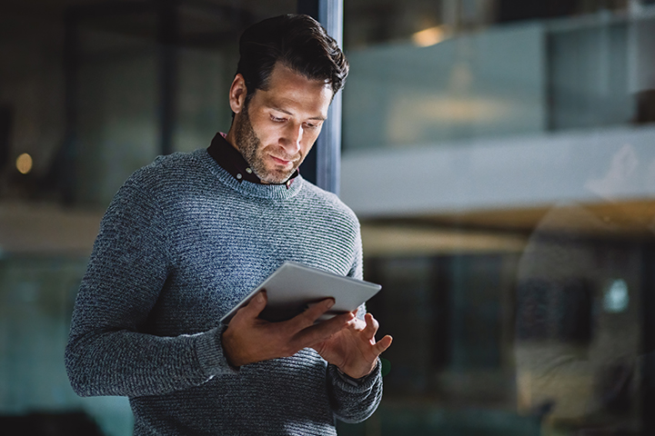 Cropped shot of a handsome mature businessman standing alone in his office and using a tablet