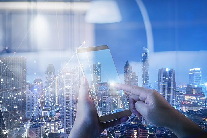 Hands touching a smartphone with smart city in the background