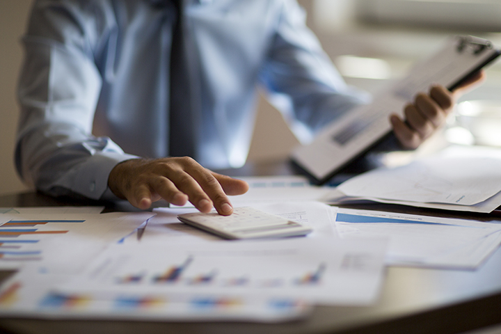 Businessman working on accounts in his office with papers and a calculator