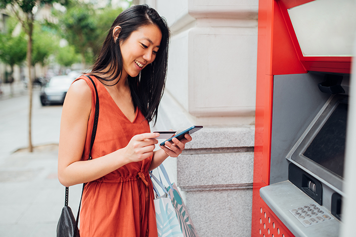 femme qui est en face d'un ATM sur son portable