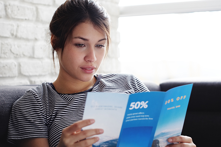 femme qui lit un brochure sur so canape