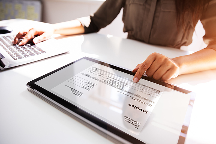 Gros plan de la main d'une femme d'affaires travaillant avec facture sur tablette numérique