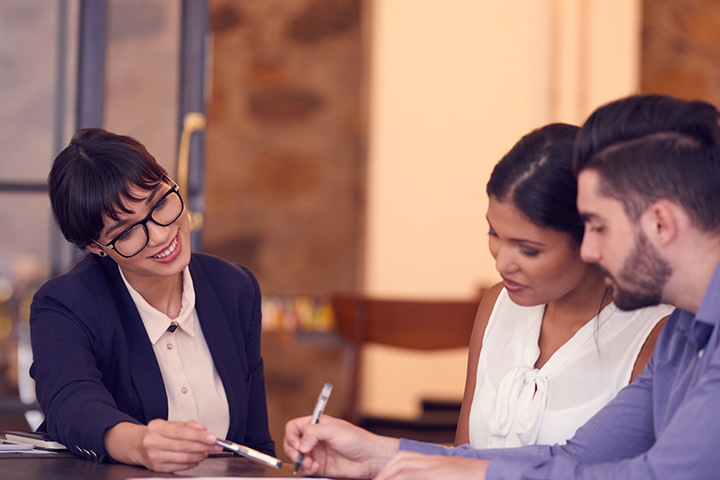 Photo d'un jeune couple rencontrant un planificateur financier dans un bureau