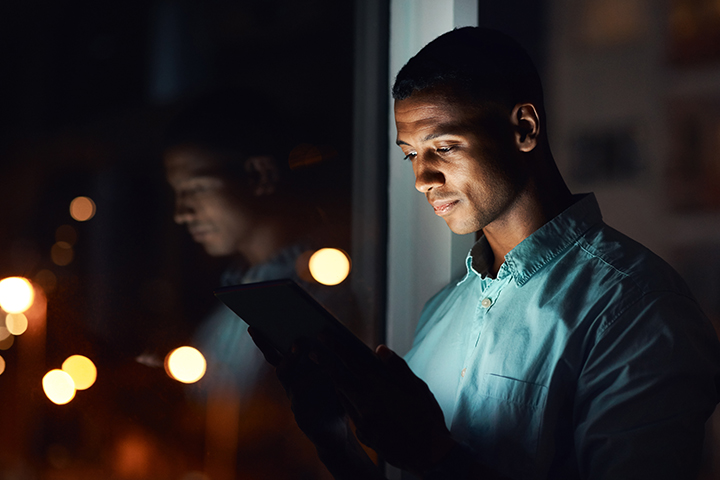 beau jeune homme d'affaires à l'aide d'une tablette numérique tout en travaillant tard dans son bureau