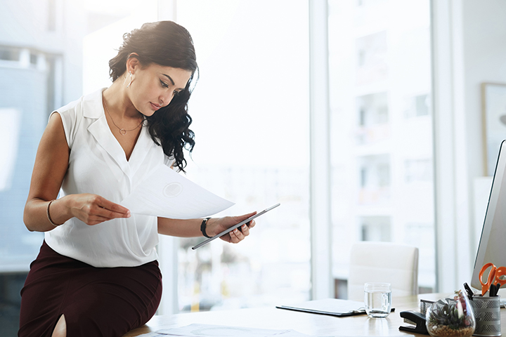woman looking at a document in her office near a window