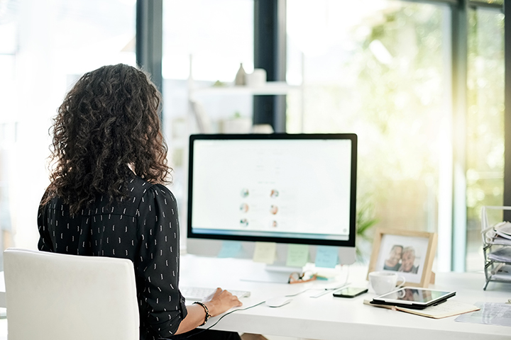 woman working at her desk and at her computer near a window 