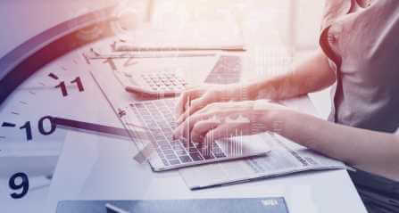 mains qui tappent sur un ordinateur, un horloge a l'arriere plan