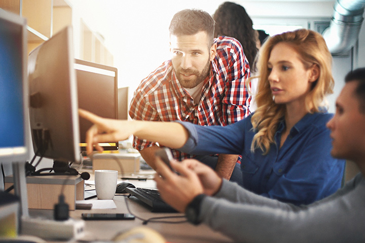 groupe de gens qui travail ensemble sur un ordinateur a leur bureau