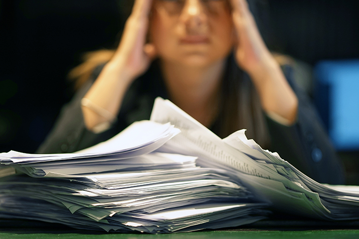 gros plan d'une employée de bureau est en détresse avec beaucoup de paperasse devant elle.
