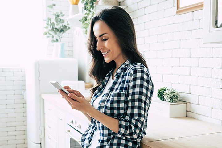 smiling woman using smart phone at home
