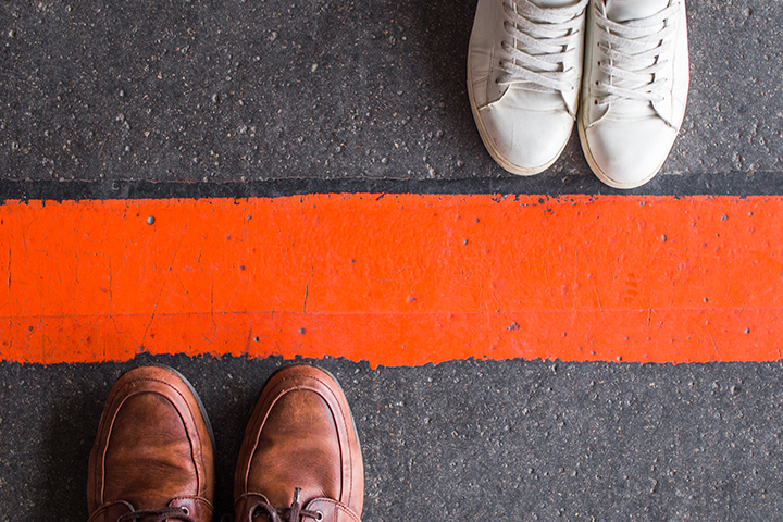 two pairs of shoes standing on either side of a barrier