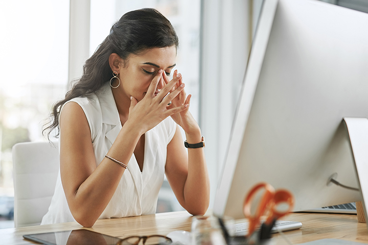 young businesswoman experiencing stress while working at her desk in modern office