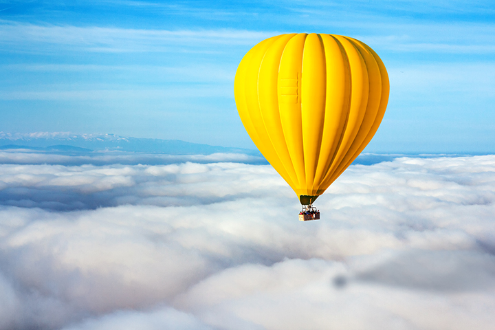 Mongolfiera gialla in un cielo limpido e blu con le nuvole