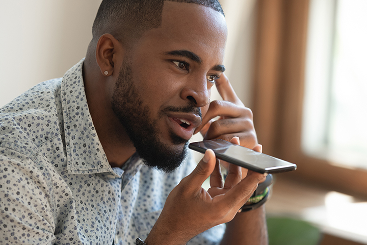 close up thoughtful guy sitting on couch and talking on speakerphone