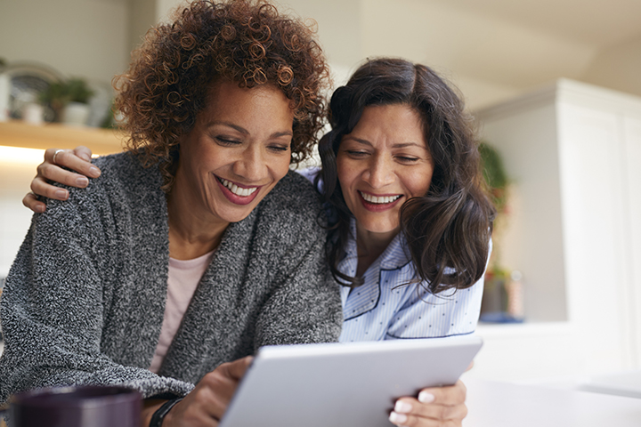 two people looking over at a computer screen smiling