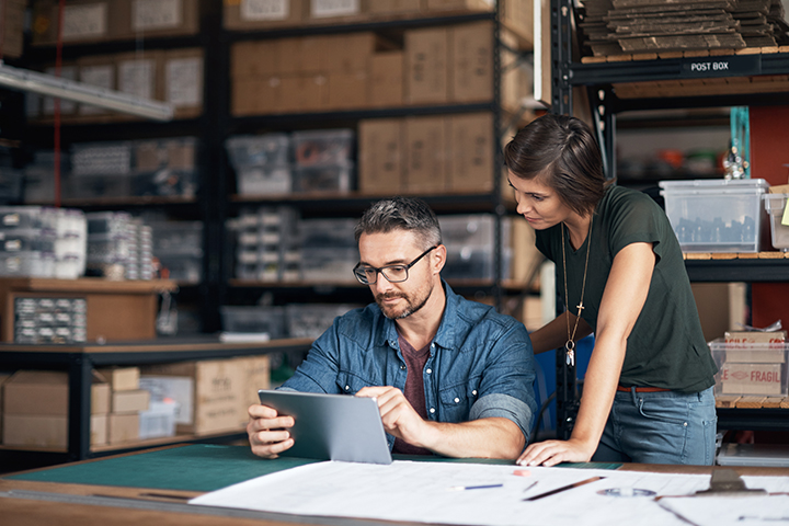 two colleagues at the warehouse reviewing shipping documents on tablet