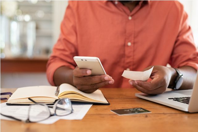 man holding a phone and a receipt