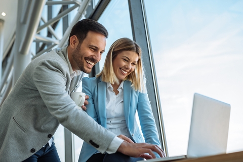 Two happy businesspeople enjoying working on a laptop, independent, empowered