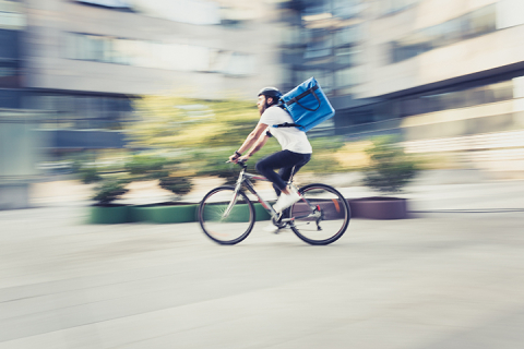 Food delivery person on bicycle going fast with blurry background