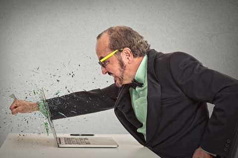 angry man punches through laptop screen