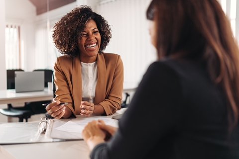 Two people sitting and laughing at a table in an office