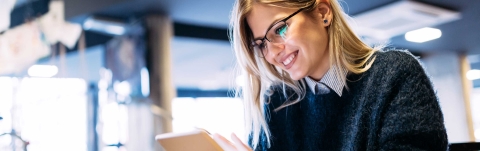 Lächelnde blonde Frau mit Brille, die einen Brief liest