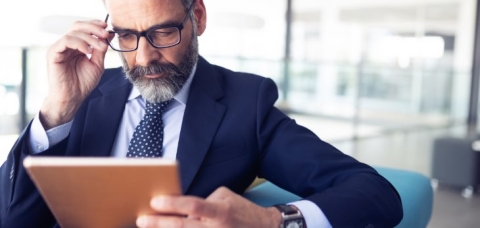 Mann mit Brille schaut auf sein Tablet