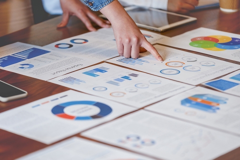 Paperwork spread out on a conference room table as people point at it
