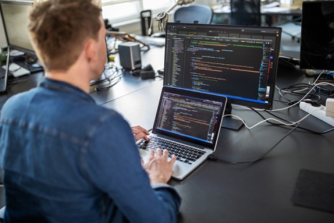 Ingénieur logiciel écrivant du code sur un ordinateur portable et de bureau à des fins de programmation d’automatisation