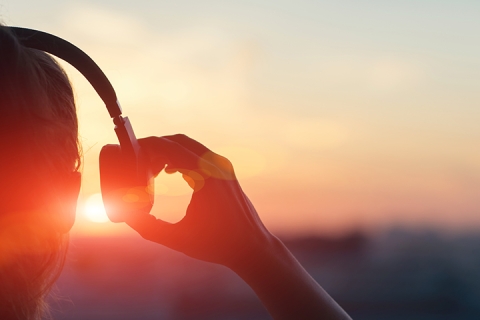 fille qui porte des ecouteurs et qui regarde le coucher du soleil