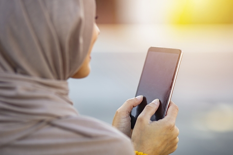 jeune femme portant le foulard hijab dans la ville envoyant des SMS au téléphone portable