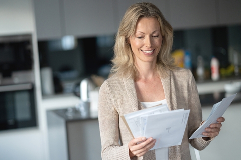 woman at home checking her mail and looking happy