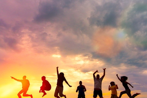 Sillhouettes of happy people jumping in front of sunset
