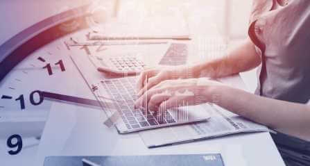 mains qui tappent sur un ordinateur, un horloge a l'arriere plan