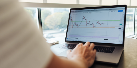 man working with a laptop looking at graphs