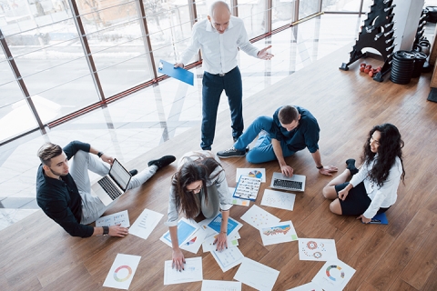 Planifier ensemble la stratégie. Équipe commerciale regardant des papiers sur le sol à la recherche d'une idée. Coopération entreprise réalisation et concept de travail d'équipe.