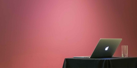 laptop sitting on a table in a room with a pink wall