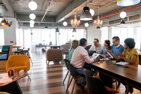 Group of working professionals discussing at a table in a meeting, engaged in conversation