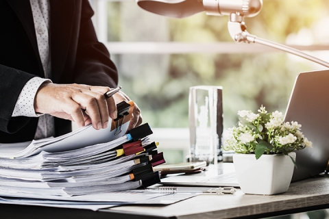 Businessman picking up report from list of files on a professional desk