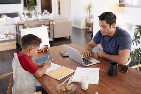 father and son working opposite each other at the dining room table