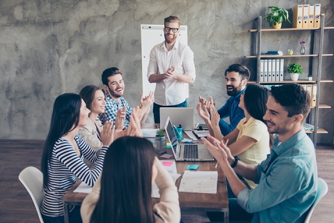 Coworkers sitting around a desk clapping