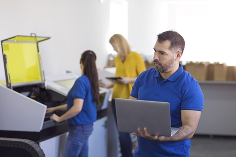 Man using laptop for data quality assurance in printing factory