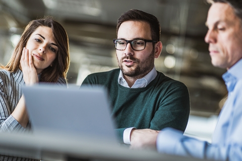 group of individuals discussing something on the computer in a professional setting