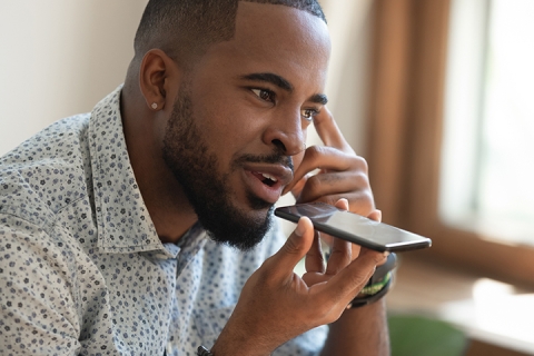 close up thoughtful guy sitting on couch and talking on speakerphone