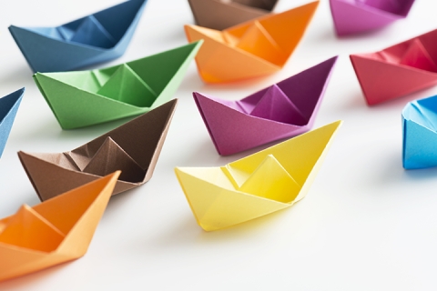 multi coloured paper boats on white background