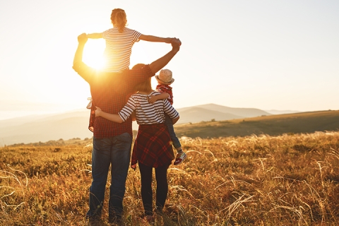 Happy family: mother, father, children son and daughter on nature walk on sunset