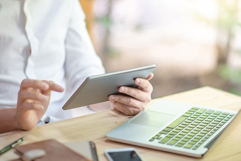Business man using digital tablet for reading news sitting with laptop