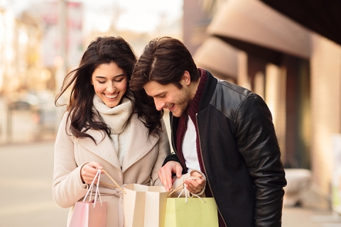 young couple looking into shopping bags after shopping in boutiques