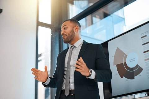 Shot of a young businessman presenting data on a screen during a meeting in an office