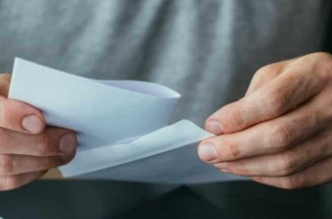 the hands of a man unfolding a sheet of paper